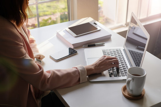 Asian Adult Entrepreneur Work On Laptop And Mobile Phone With Paperwork In The Smart Office