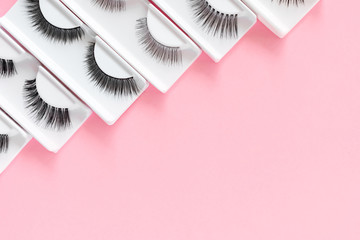 Different false eyelashes on a trendy pastel pink background. Beauty pattern. Makeup accessories....