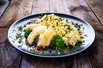 Risotto with fried cod loin on wooden background
