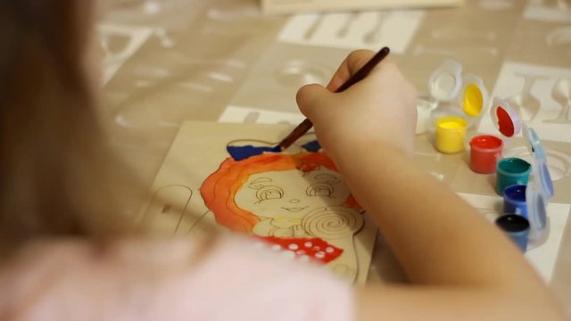 Little girl draws a picture using a paint brush. Child painting art