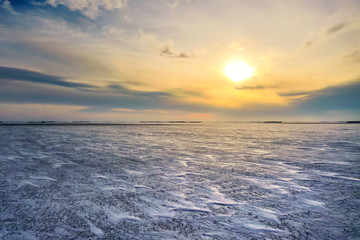 Frozen Canadian winter landscape with sun traveling low in the sky with lots of blowing snow.