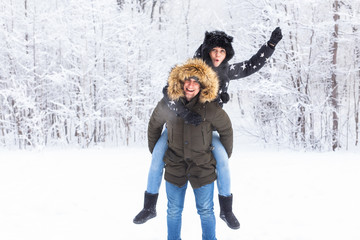 Fototapeta premium Portrait of happy young couple in winter park with their friend behind