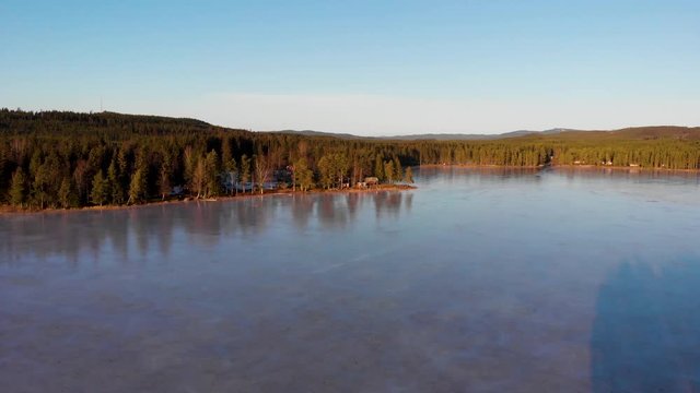 Drone moving forward over the ice covered lake Busjon outside Applebo in Vansbro kommun on a sunny winter day.