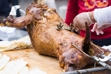 Cutting the mutton hulk fried on a grill for the pilaf. Male hands keep a knife in gloves and cut meat