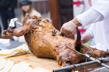 The carcass of a lamb is roasted on a spit. Close-up carcass of a sheep that is roasting on the spit.