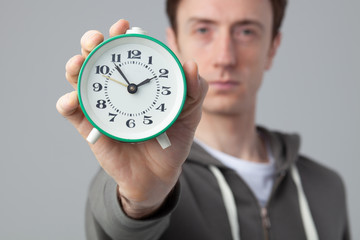 serious man holding vintage alarm clock isolated on gray background