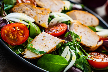 Caesar salad - barbecue chicken breast and vegetables on wooden table