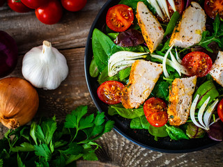 Caesar salad - barbecue chicken breast and vegetables on wooden table