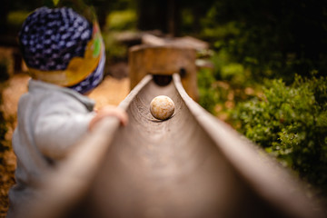 Small Child standing at a big wooden ball path in the Zillertal, Austria in the alps.