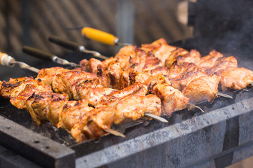 Delicious bbq kebab grilling on open grill, outdoor kitchen. Food festival in city. Tasty food roasting on skewers, food-court. Summer picnic