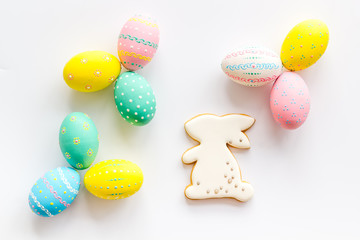 Easter background. Painted eggs and bunny on white desk top-down
