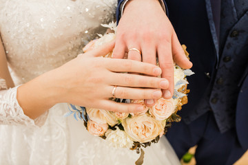 wedding rings on your hand. Newlyweds put their hands on the wedding bouquet, showing off their wedding rings.