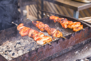 Delicious bbq kebab grilling on open grill, outdoor kitchen. Food festival in city. Tasty food roasting on skewers, food-court. Summer picnic