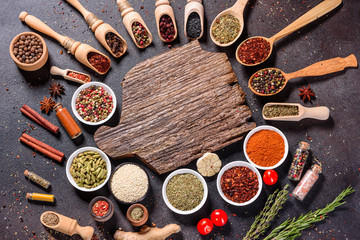 Spices and herbs over black stone background. Top view with free space for menu or recipes