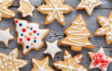 Homemade Christmas cookies in shape of star, spruce and snowflakes with white icing on wooden gray background, close-up