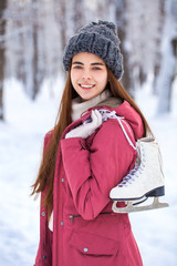 Happy beautiful brunette woman with ice skates go to the rink, winter outdoors