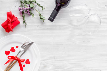Romantic dinner on Valentines Day. Wine, plate, present box on white background top-down copy space