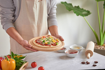 Raw pizza with ingredients in the background