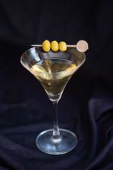 Martini cocktail with green olives on marble board. Close up.Classic glass of dry Martini with three olives