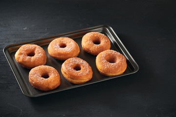 Donuts with sugar on a tray in a bar