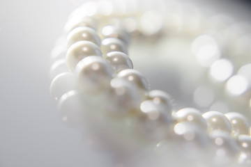 A necklace of pearls lying on white glass