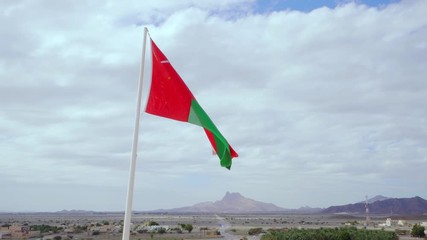 Flag of Oman Waving Against Blue Sky. Symbol of Independence and Sovereignty of Omani Sultanate