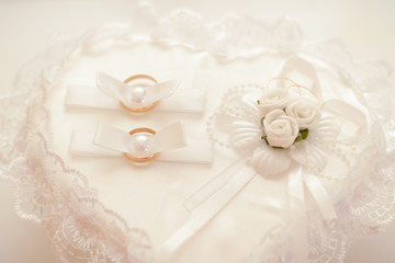 Gold wedding rings on a white holiday pillow