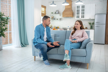 Father and daughter sitting on the couch talking.