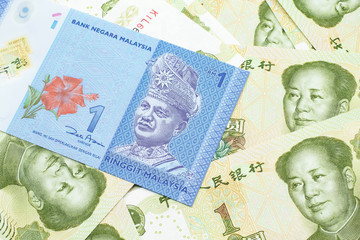 A close up image of a blue one Malaysian ringgit bank note on a bed of Chinese one yuan bank notes close up in macro