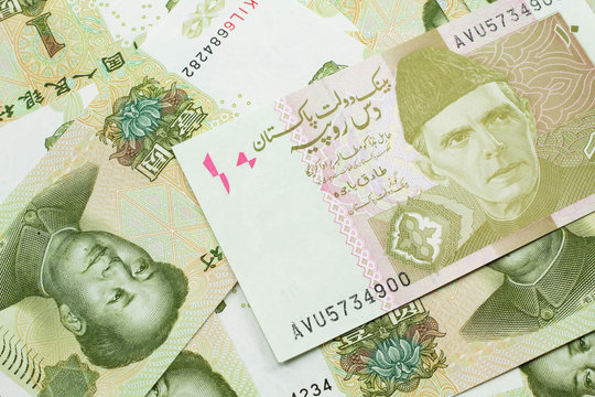A close up image of an orange and ten Pakistani rupee bank note with Chinese one yuan bills in macro