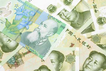 A close up image of a green Romanian one leu bank note on a background of Chinese one yuan bank notes