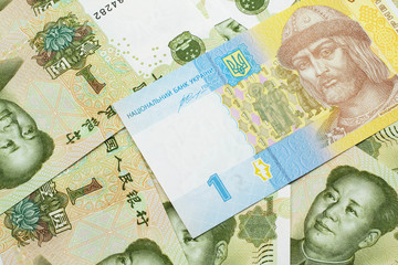 A blue and yellow one Ukrainian hryvnia bank note on a bed of Chinese one yuan bank notes