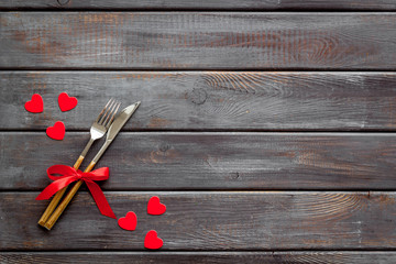 Valentines' Day dating in restaurant concept. Fork and knife decorated with hearts on wooden background top-down copy space