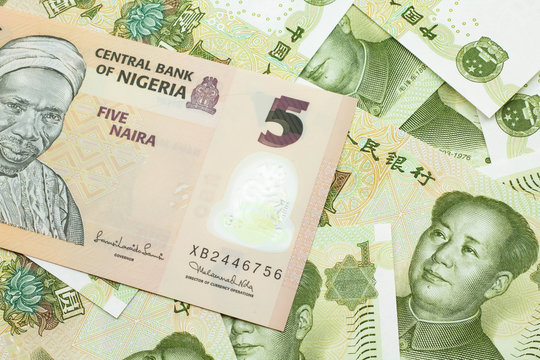 A close up image of a peach colored, five Nigerian naira bank note on a background of Chinese one yuan bank notes