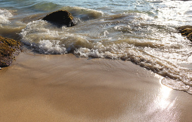 Beach idyll, sand and stones, bright sun glare on the waves