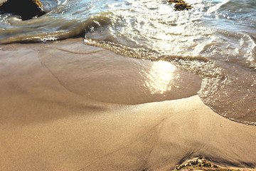Beach idyll, sand and stones, bright sun glare on the waves