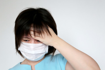 Sick woman in medical mask holds hand to her forehead. Concept of illness, fever, cold and flu, head pain, coronavirus symptoms