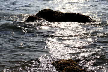 Beach idyll, sand and stones, bright sun glare on the waves