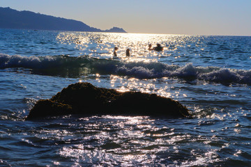 Beach idyll, sand and stones, bright sun glare on the waves