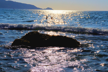Beach idyll, sand and stones, bright sun glare on the waves