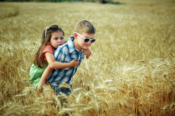 Naklejka na ściany i meble Children on a walk in a field with wheat . Brother and sister on vacation in the countryside