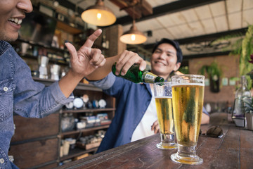 A man wearing a denim shirt and a glass of beer in the bar	