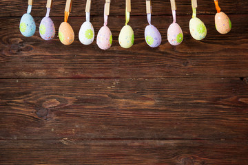 Easter eggs hanging on string over brown rustic wooden wall