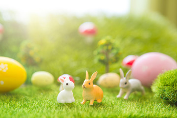 Little Easter bunny toys and Easter eggs on green grass