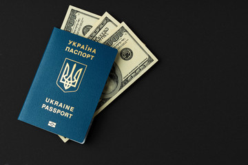 Fototapeta premium Ukrainian passport with US dollars banknotes on black background