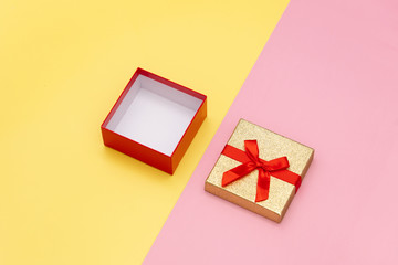 Obraz premium Little open gift box on pink and yellow backgrounds.