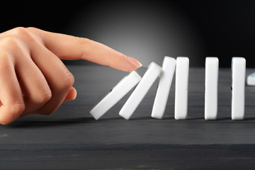 Woman hand toppling dominoes. Chain reaction business concept