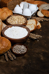 assortment of baked goods and fresh bread on dark background, vertical