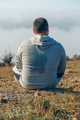 Tired man hiker sits on a mountain and relaxes