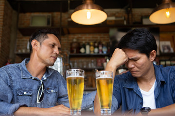 A man wearing a denim shirt and a glass of beer in the bar	